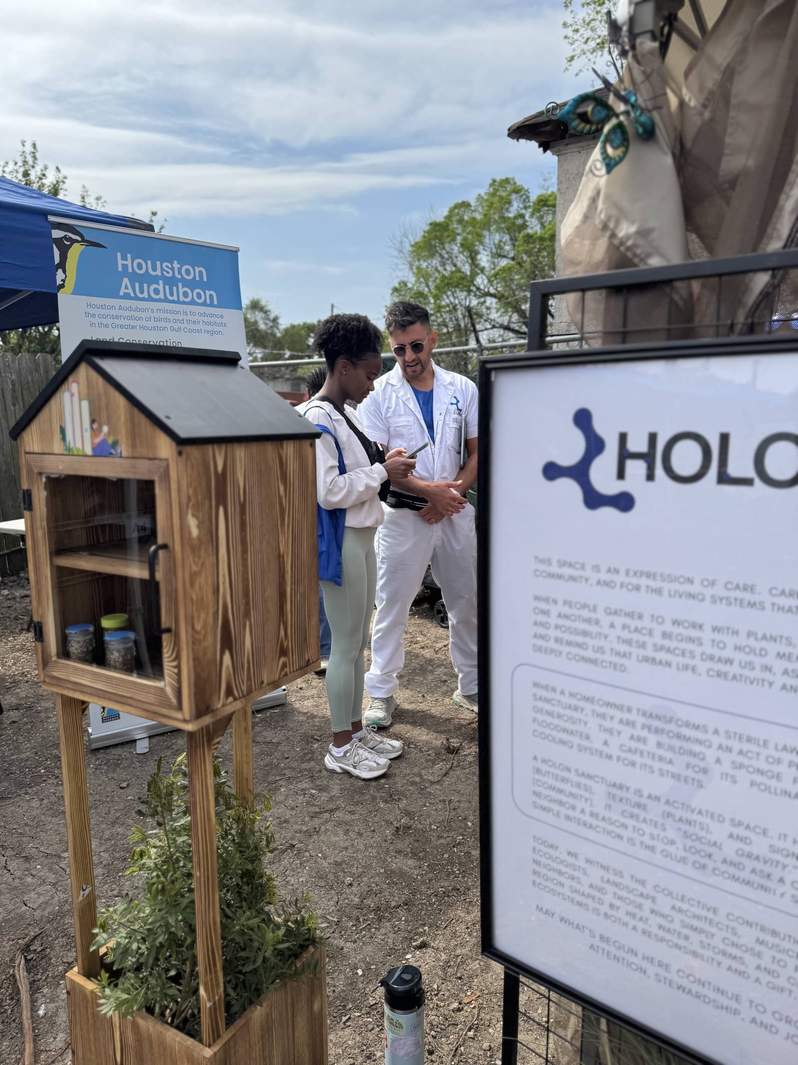 A small wooden seed library house on a stand at a festival booth